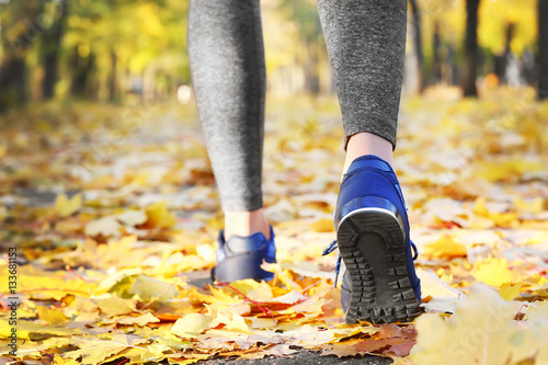 Legs of young sporty woman in autumn park, close up view