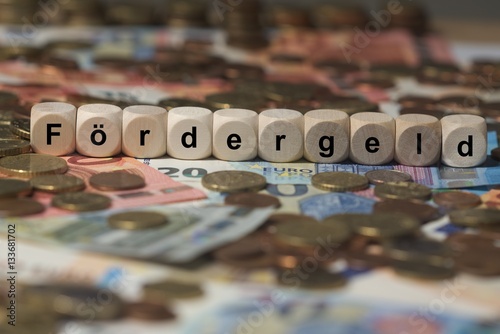 fördergeld - Holzwürfel mit Buchstaben im Hintergrund mit Geld, Geldscheine