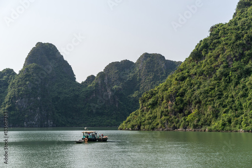 Beautiful landscape of lagoon in the Ha Long Bay (Descending Dragon Bay) at the Gulf of Tonkin of the South China Sea, Vietnam. Scenic landscape formed by karst towers. Small fishing boat.
