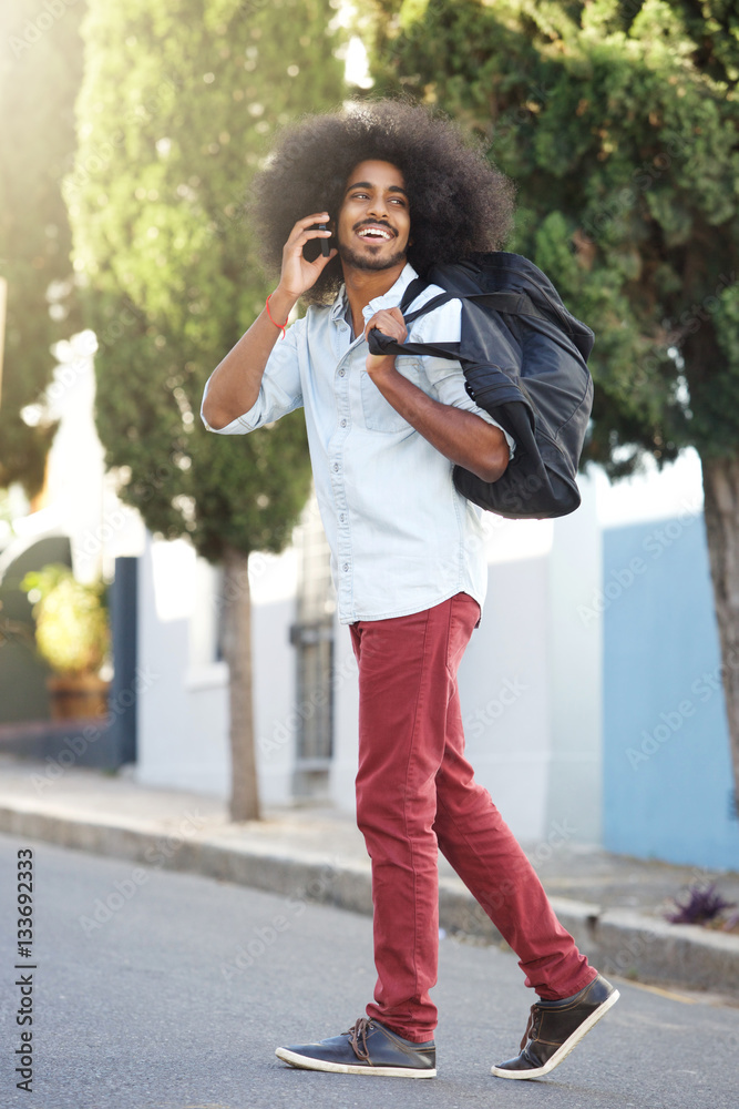 Fototapeta premium happy man walking outside with phone and bag