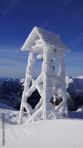 Wieża z dzwonem pokryta lodem na szczycie góry.