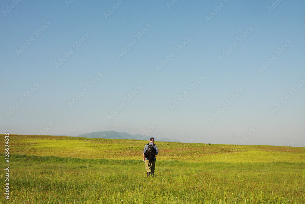 A man is hiking on field background, sunny and blue sky A man is hiking on field background, sunny and blue sky