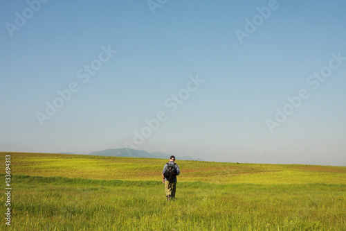 A man is hiking on field background, sunny and blue sky © apismellifera