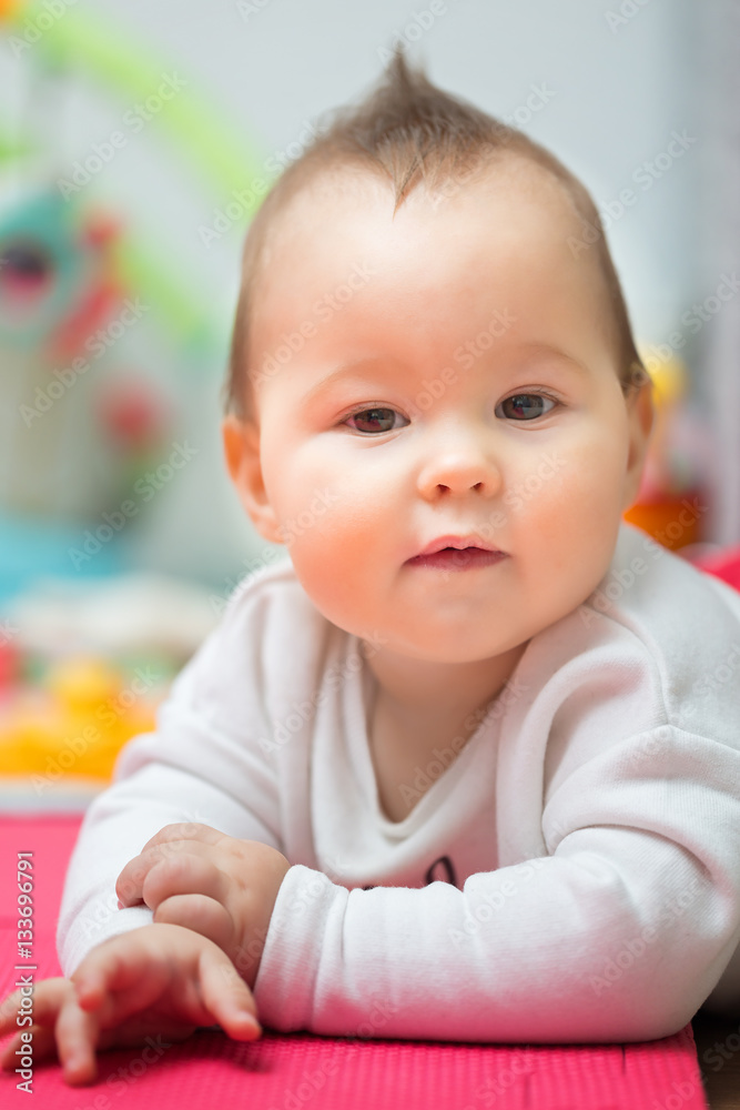 Eight months old baby girl laying on her belly on the floor mat, Eight months old baby girl laying on her belly on the floor mat,