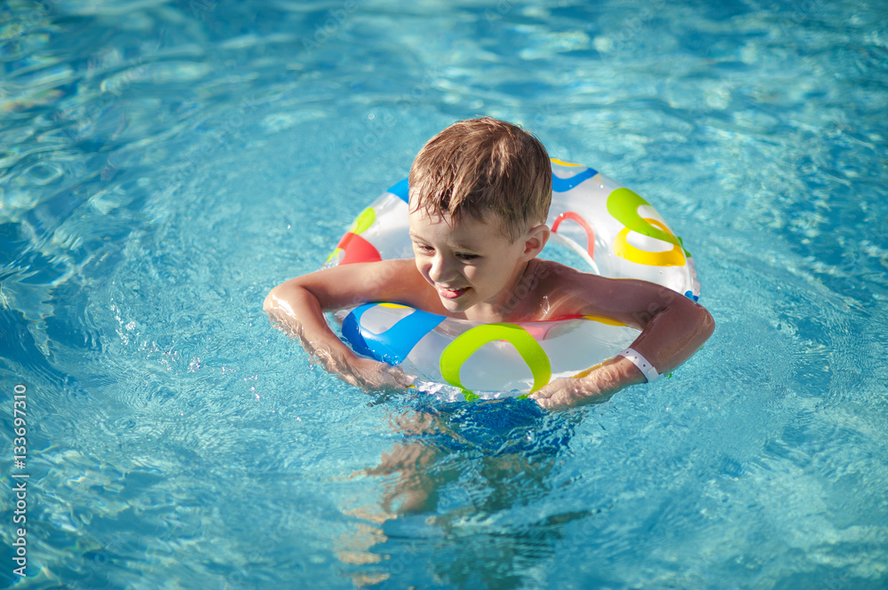 Happy boy with a life ring enjoying  in the swimming pool.