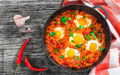 shakshuka - fried eggs, onion, bell pepper, tomatoes, chili photo