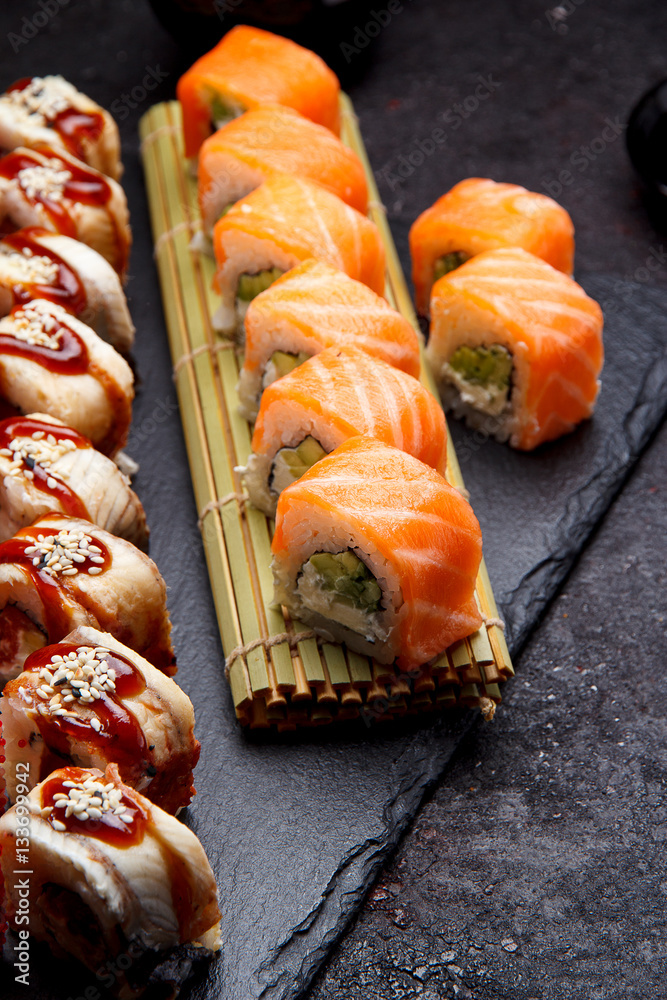 Japanese cuisine. Sushi roll with fresh ingredients on a stone plate and background. Japanese cuisine. Sushi roll with fresh ingredients on a stone plate and background.