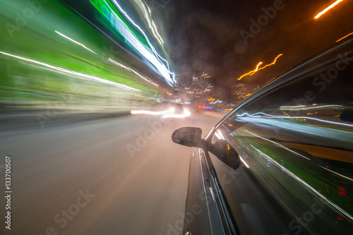 View from Side of Car moving in a night city, Blured road with lights with car on high speed. Concept rapid rhythm of a modern city.