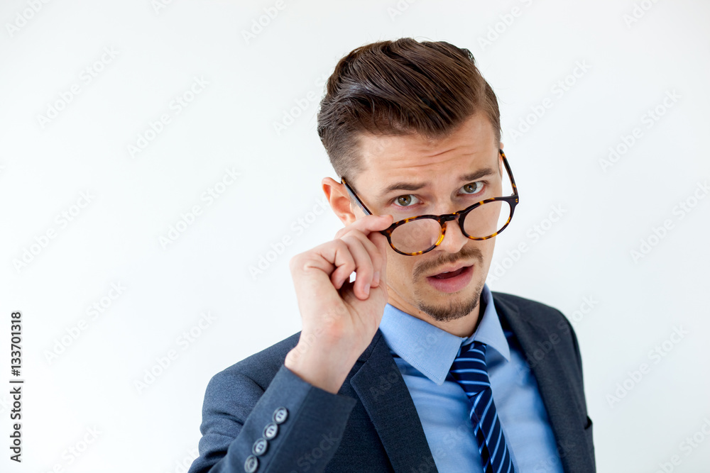 Surprised young businessman looking over glasses Surprised young businessman looking over glasses