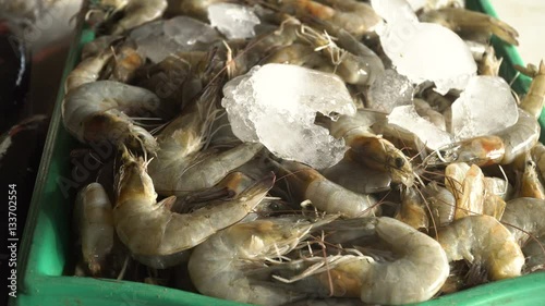 Shrimp on ice on the counter of the Asian street market. Freshly caught shrimps or Parapenaeus longirostris on the counter with ice at the fish shop. The raw shrimps in fish shop for sale. 4K video photo