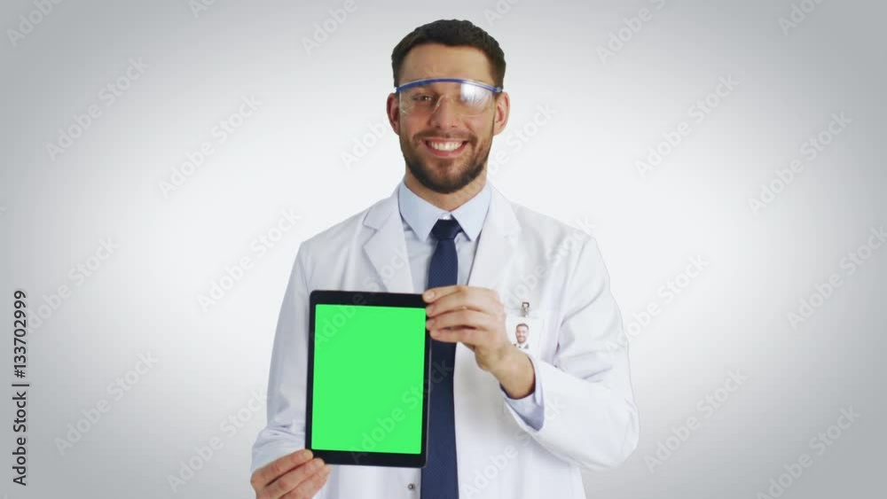 Mid Shot of a Smiling Scientist Presenting To Us Tablet Computer with Isolated Mock-up Green Screen. Shot with White Background. Shot on RED Cinema Camera 4K (UHD). Mid Shot of a Smiling Scientist Presenting To Us Tablet Computer with Isolated Mock-up Green Screen. Shot with White Background. Shot on RED Cinema Camera 4K (UHD).