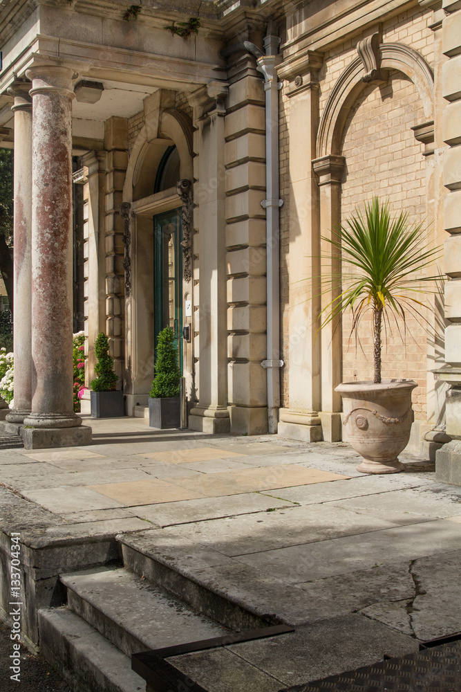 Fototapeta premium Porch building with columns. Refined Architecture. Palm tree in a pot.