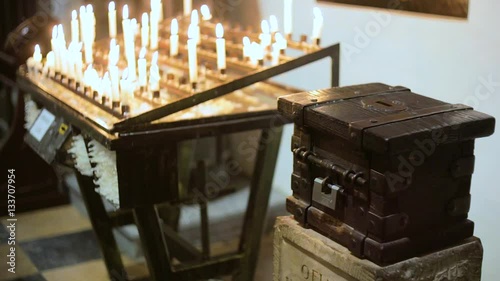 donation box near burning candles in a church photo