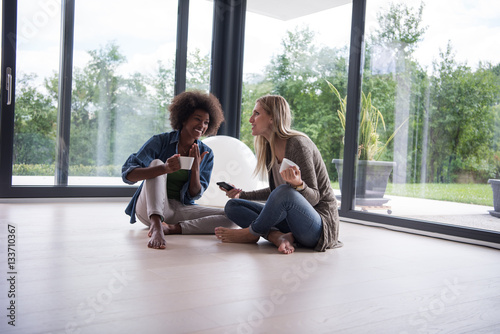 multiethnic women sit on the floor and drinking coffee