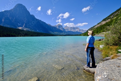 Woman looking at the beautiful view of clear turquoise lake and rocky mountains. Waterfowl lake. Canadian Rockies. Banff National Park. British Columbia. Canada.