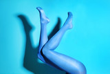 Beautiful woman legs in color tights on blue background