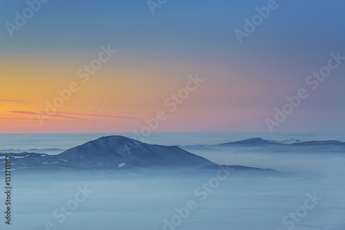 Majestic winter view with sunset over the misty valleys of the Carpathians mountains, Transylvania region, Romania.