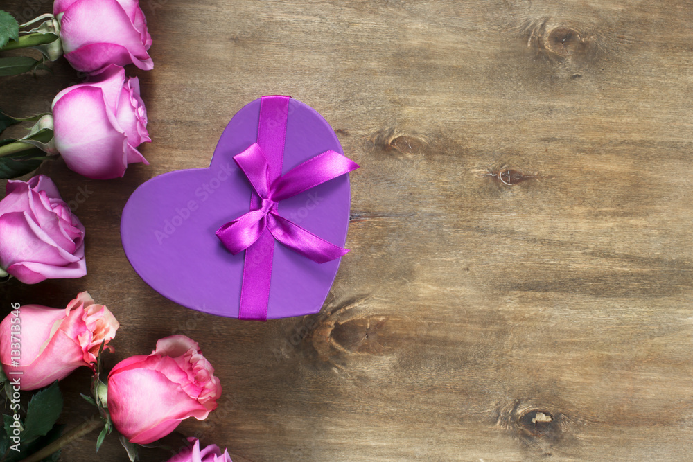 Purple and yellow roses, box present on wooden background