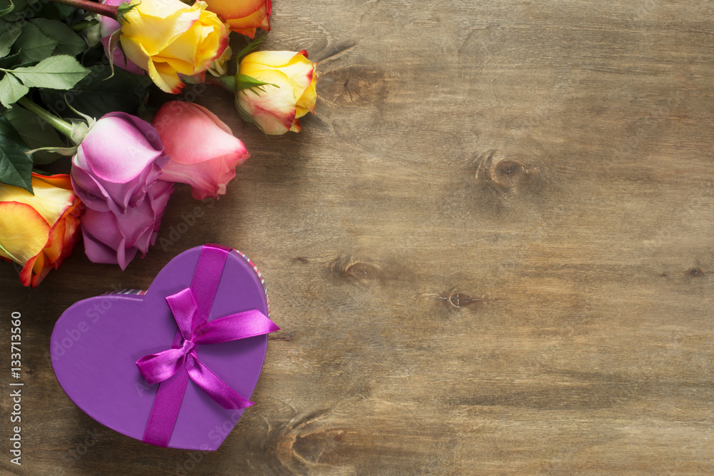 Purple and yellow roses, box present on wooden background Purple and yellow roses, box present on wooden background