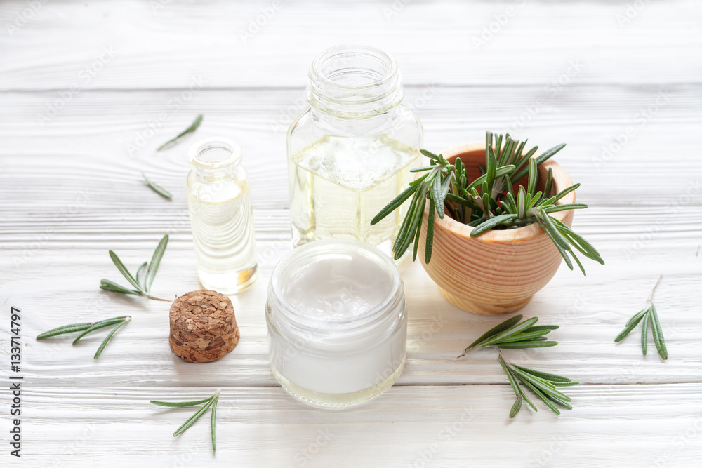 organic cosmetics with extracts of herbs rosemary on wooden background