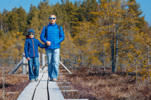 Cute little boy with father walking on trail in swamp, Kemeri national park, Latvia photo