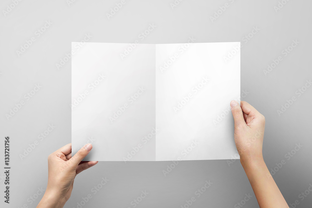 Woman hand holding blank paper sheet A4 size or letter paper on grey background. Woman hand holding blank paper sheet A4 size or letter paper on grey background.