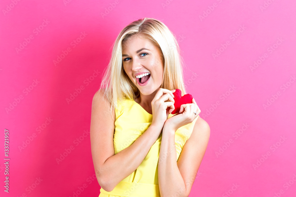 Happy young woman holding a heart cushion Happy young woman holding a heart cushion