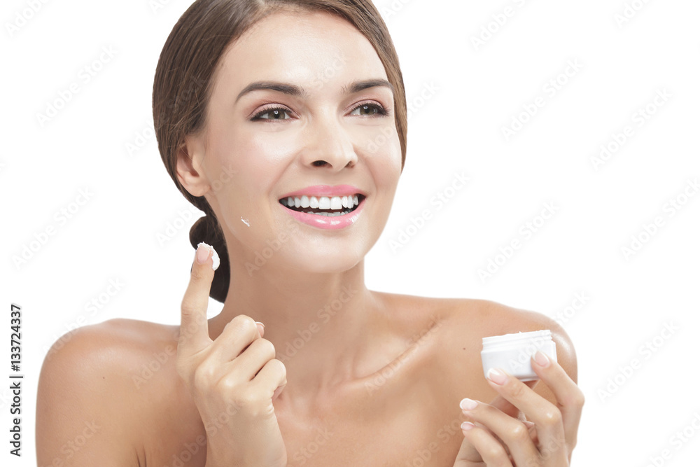 beautiful woman applying some facial cream while smiling beautiful woman applying some facial cream while smiling