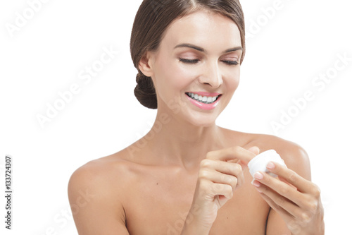 beautiful woman smiling while taking some facial cream