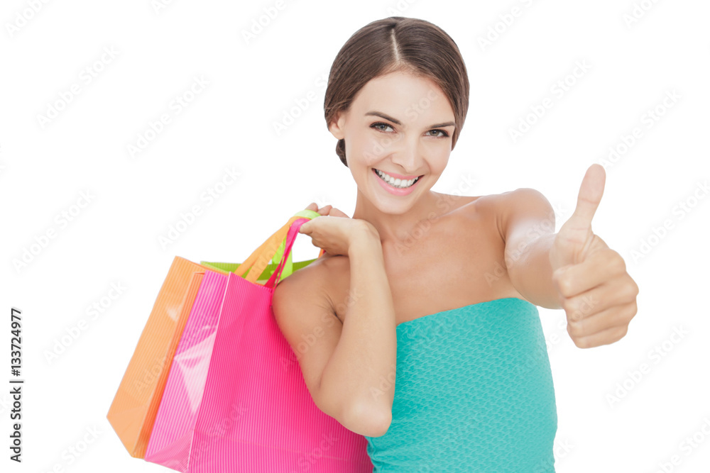beautiful young woman carrying shopping bags and giving thumbs u