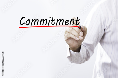 Businessman hand writing commitment with red marker on transpare photo