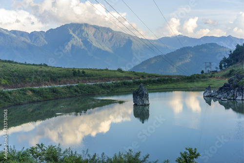 Sunset scene with calm water surface, white cloud and mountains in Than Uyen, Yen Bai, Vietnam photo