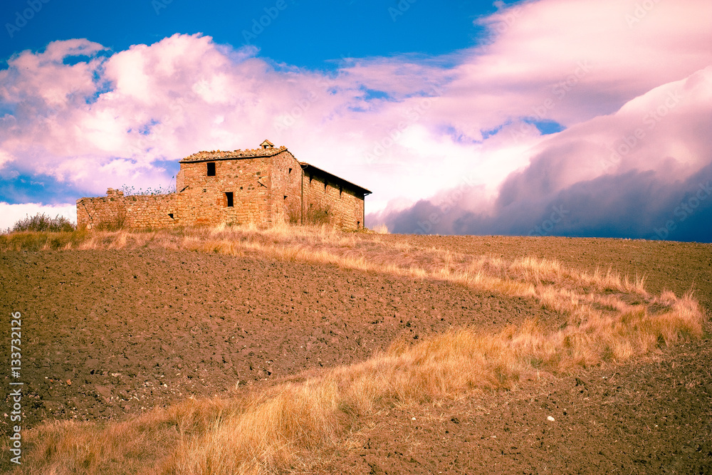 Old abandoned stone farmhouse building with path and dramatic sky from Italy countryside farm.