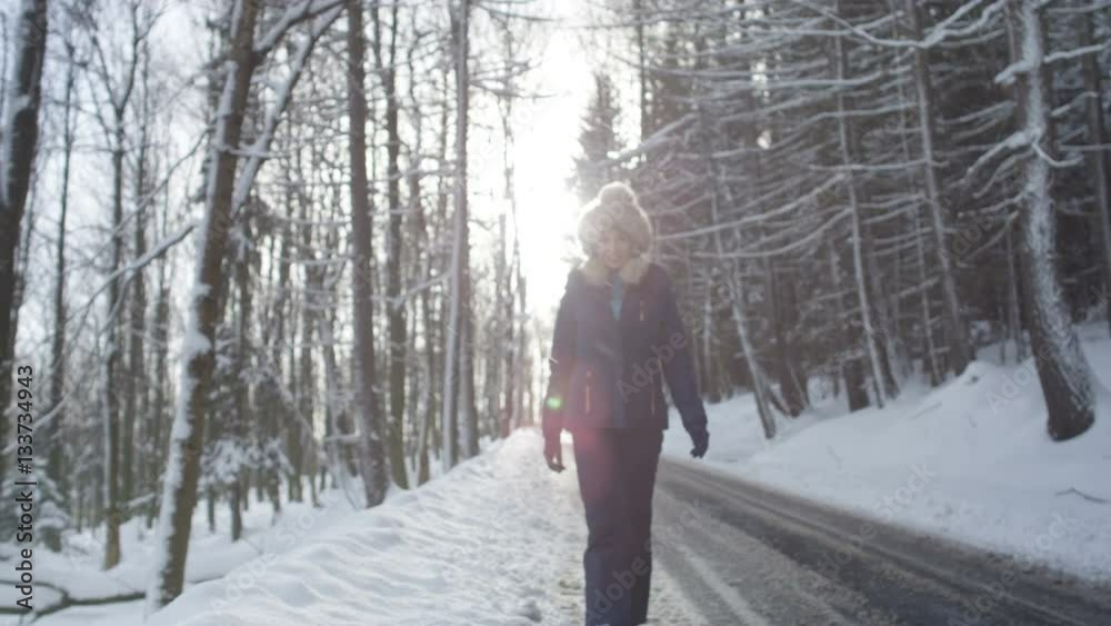 Woman wearing warm clothes walking in a cold winter snow forest. Trees on background. Shot on Red Epic. Woman wearing warm clothes walking in a cold winter snow forest. Trees on background. Shot on Red Epic.