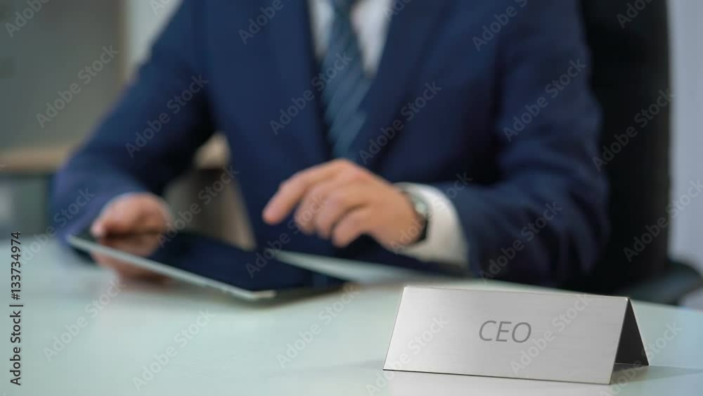 Company CEO working on tablet pc, checking email or reading business news online Company CEO working on tablet pc, checking email or reading business news online