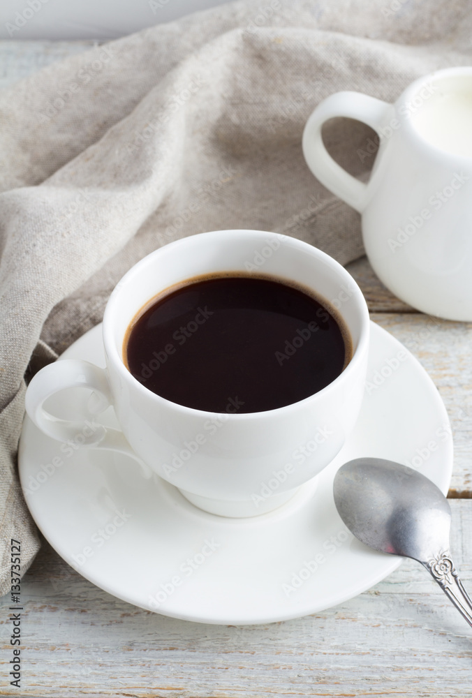 Black coffee in a cup, coffee beans, milk jug on a white background