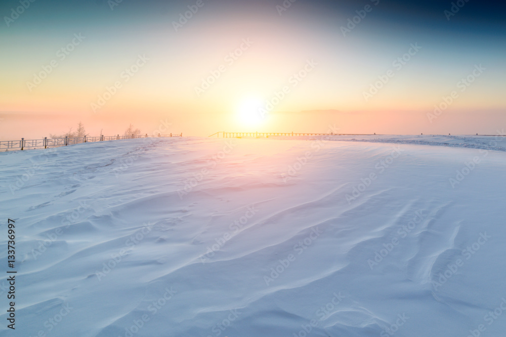 Sunny sunrise over the snowy plain.