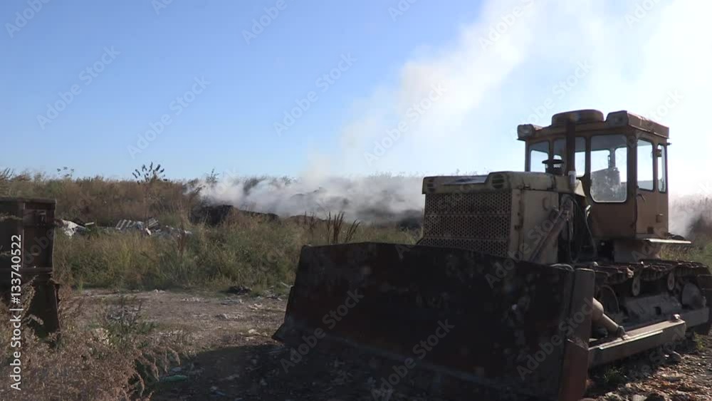 Bulldozer on garbage dump. Smoke on the background. Bulldozer on garbage dump. Smoke on the background.