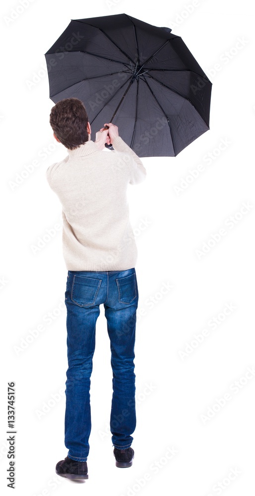 Back view of man in jeans under an umbrella. Standing young guy. Rear ...