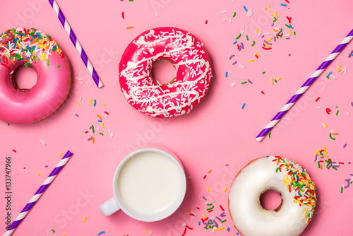 Donuts with icing and milk on pastel pink background. Sweet donu