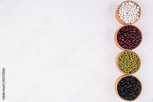Assortment of kidney beans in a wooden bowls with copy space on white wood background. Top view, closeup. Healthy protein food. © finepoints