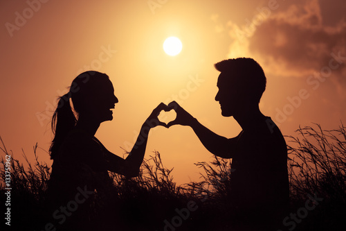 Love and relationships concept. Young happy couple outdoors making a heart shape.