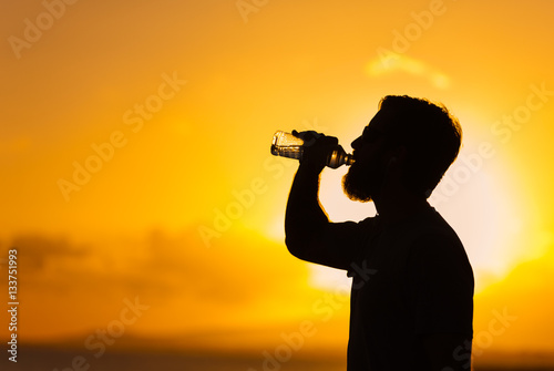 Man drinking a bottle of water after exercising. 