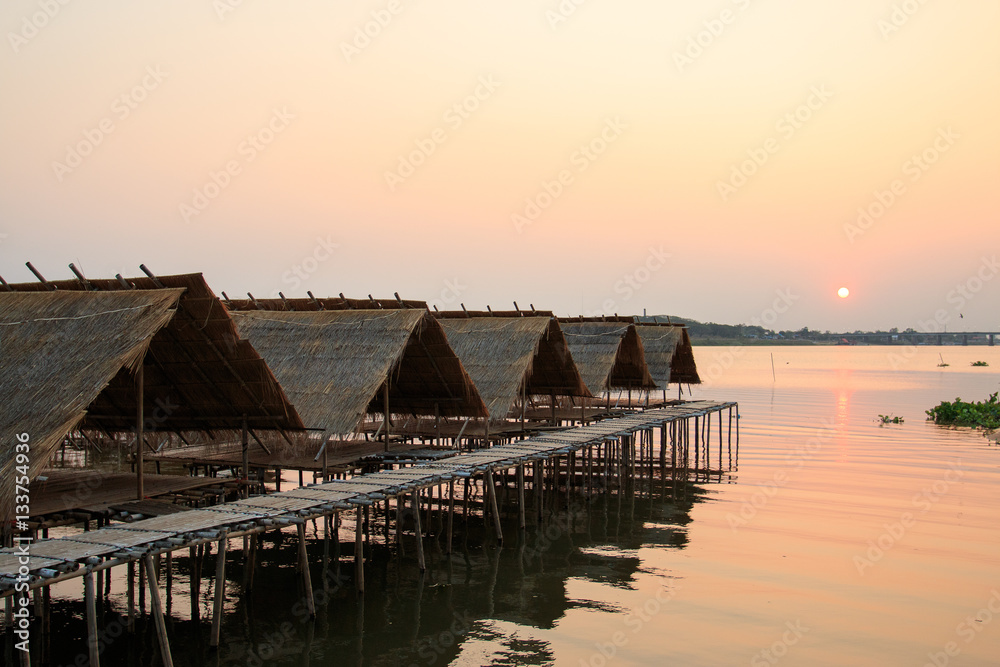 Obraz premium Huts over water with sunset