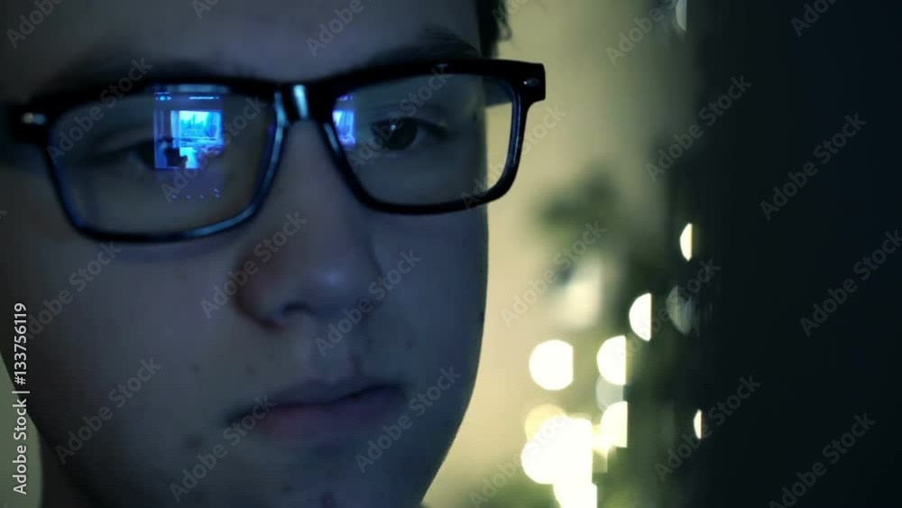Young boy with glasses browsing photos on smartphone at night
Young boy with glasses browsing photos on smartphone at night