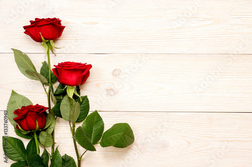 3 red roses on white aged table