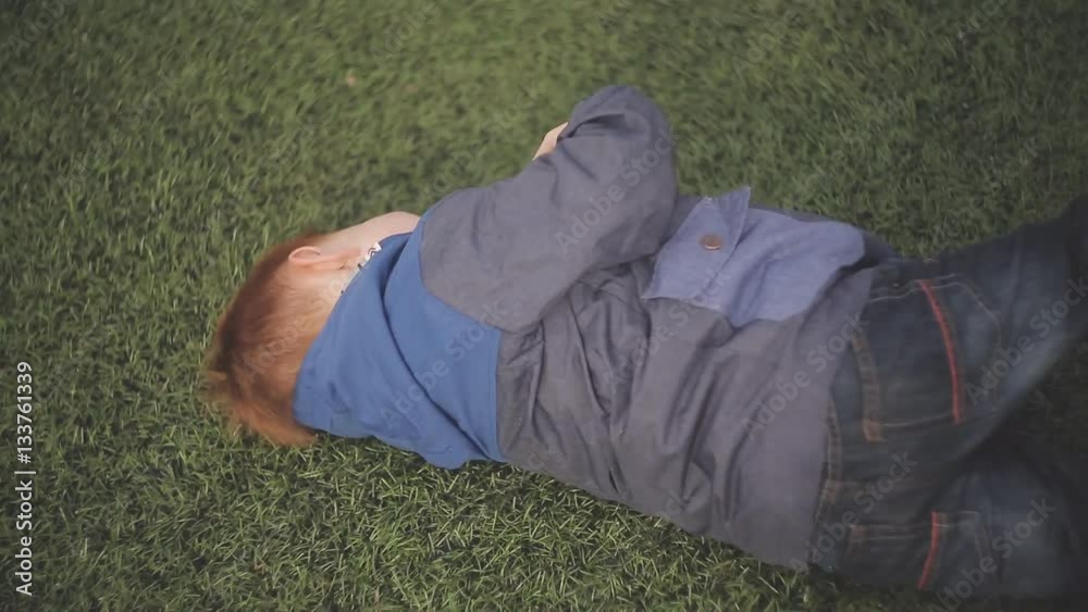 the red-haired boy with her mother playing on the green grass sport stadium the red-haired boy with her mother playing on the green grass sport stadium