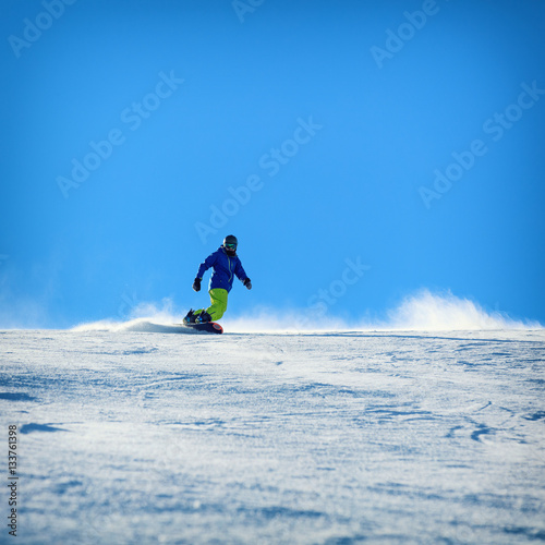 Male snowboarder on the slope sliding down the hill