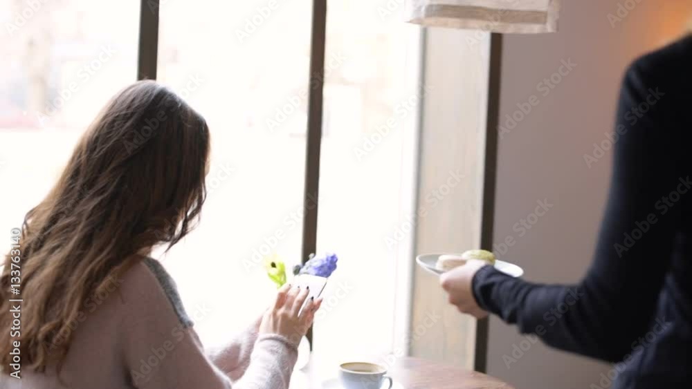Beautiful young woman sitting in cafe and getting some coffee and pastries from a waiter Beautiful young woman sitting in cafe and getting some coffee and pastries from a waiter