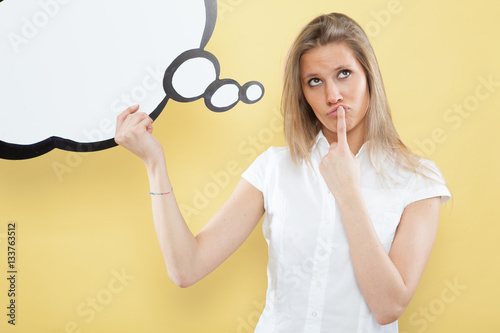 pretty young blond caucasian woman thinking with comic baloon on yellow background